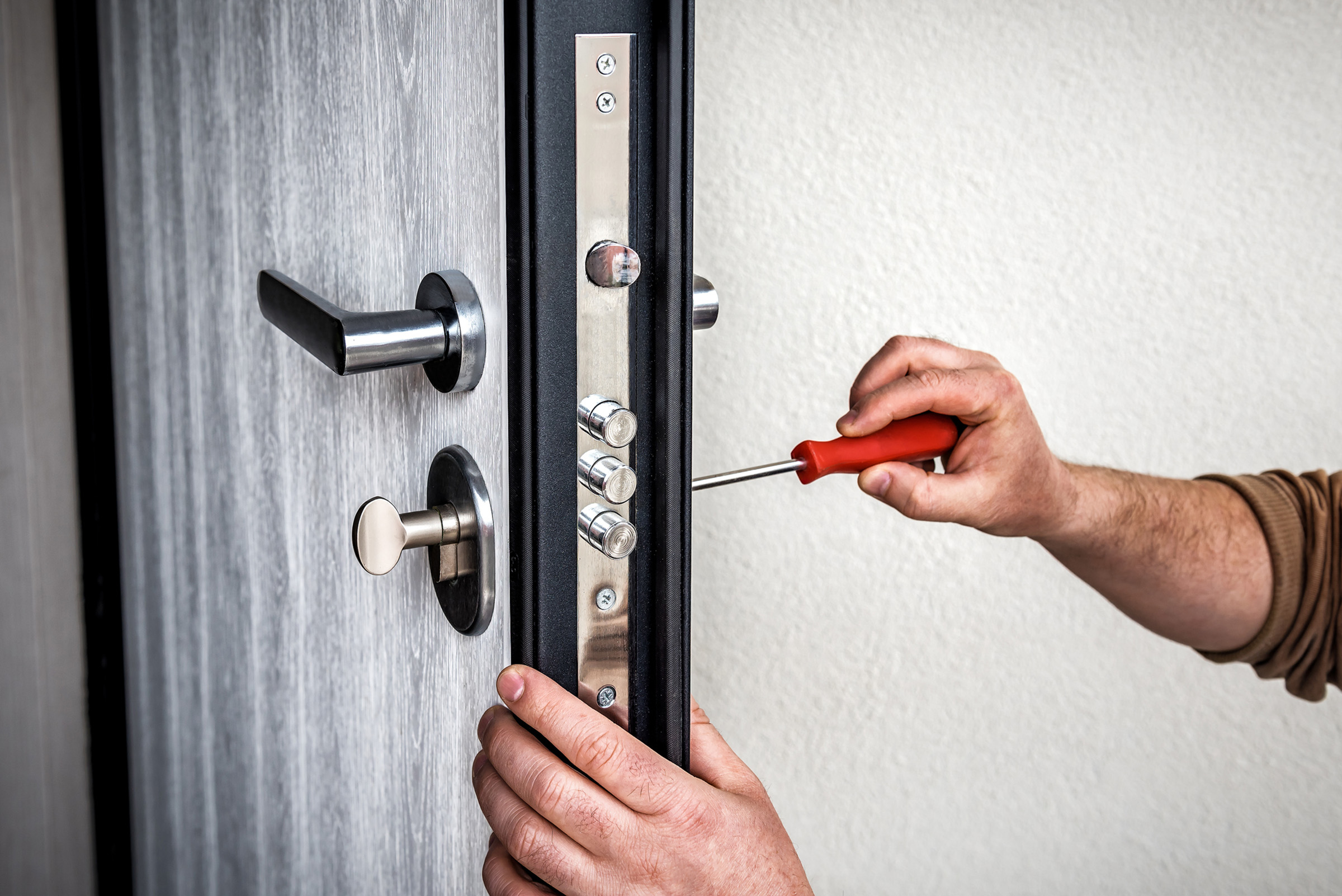 Handyman repair the door lock in metal entrance door, Man fixing lock with screwdriver locksmith fixing door